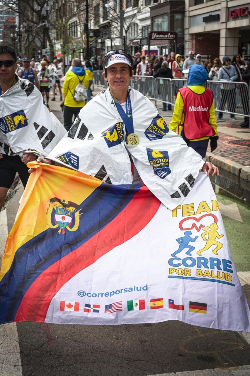 Dr. Fredy Báez sosteniendo la bandera de Corre por Salud tras Boston Marathon